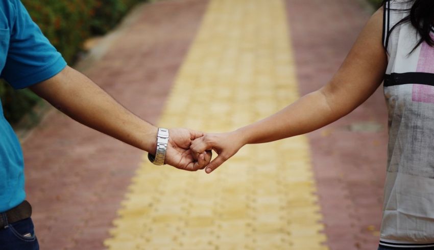 A man and woman holding hands while walking down a path.