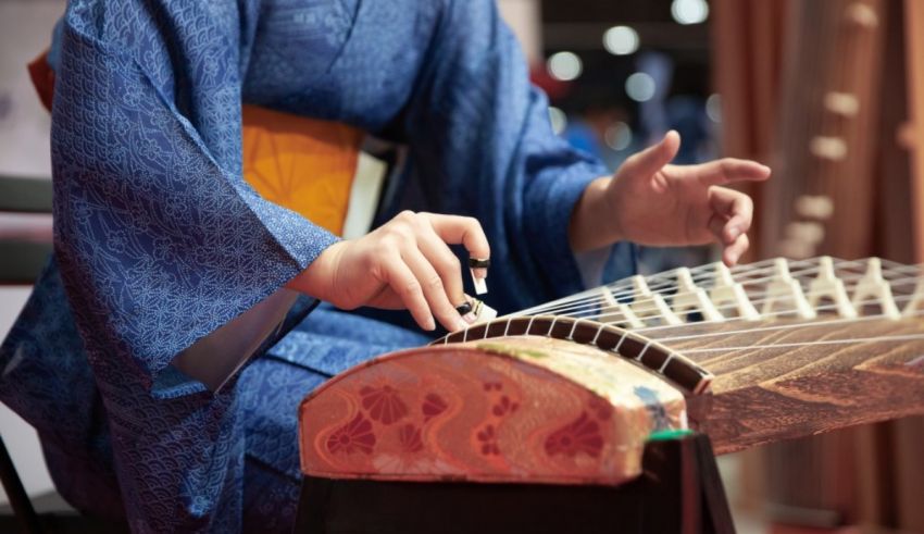 A woman in a blue kimono is playing a musical instrument.