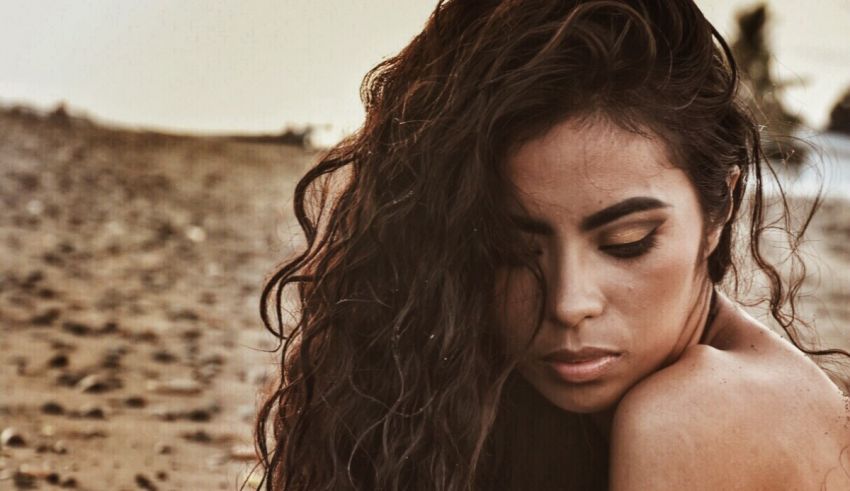 A woman with long curly hair laying on the beach.