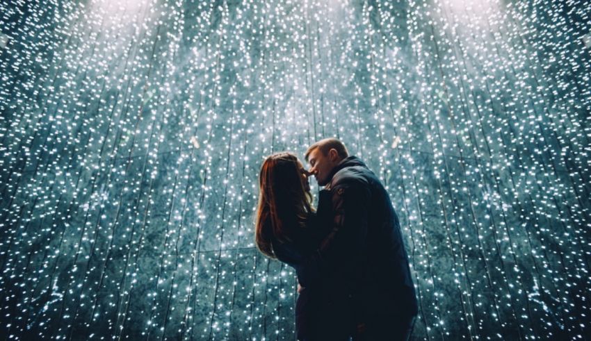 A couple kissing in front of a starry sky.