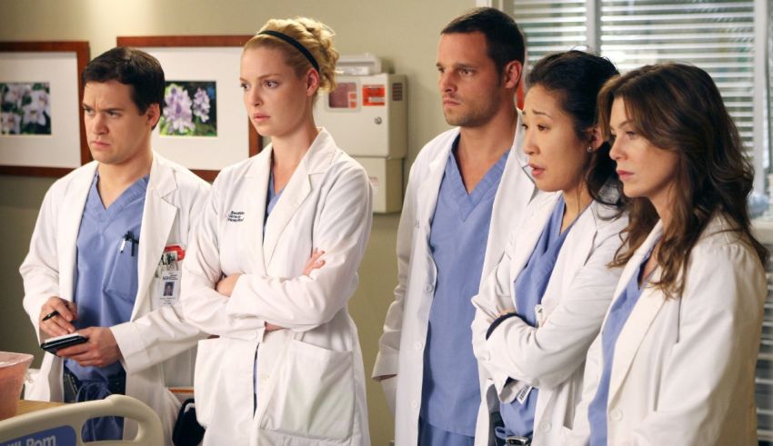 The cast of grey's anatomy standing in a hospital room.