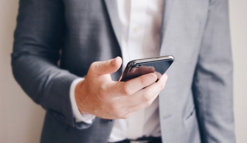 A man in a suit is holding a cell phone.