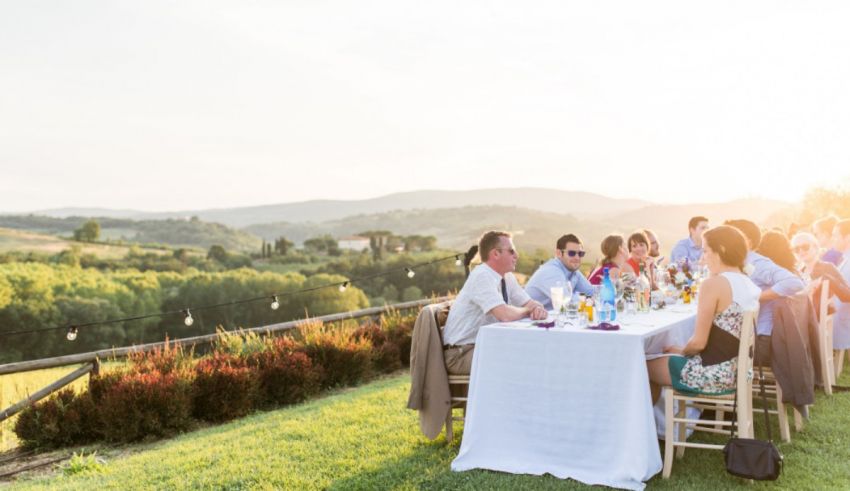 A group of people sitting at a table in the countryside.