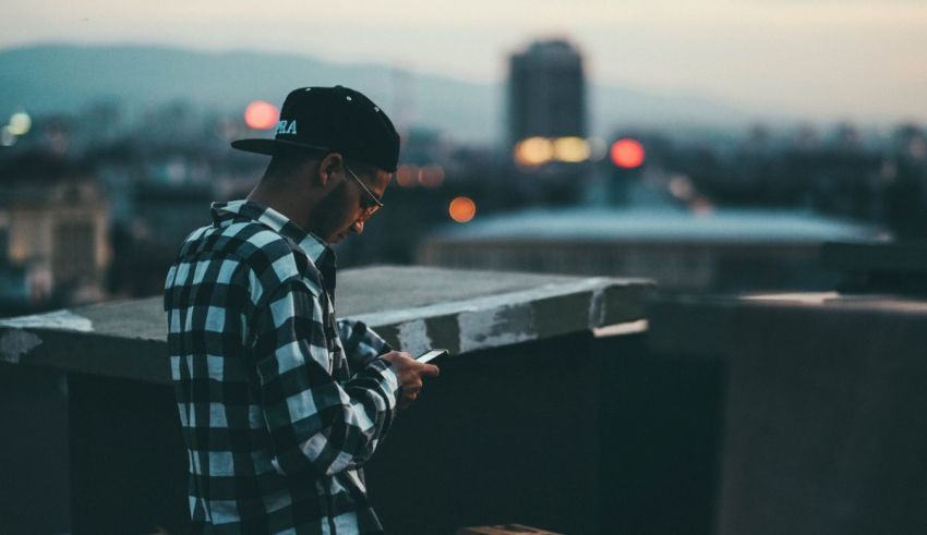 A man on a rooftop looking at his phone.