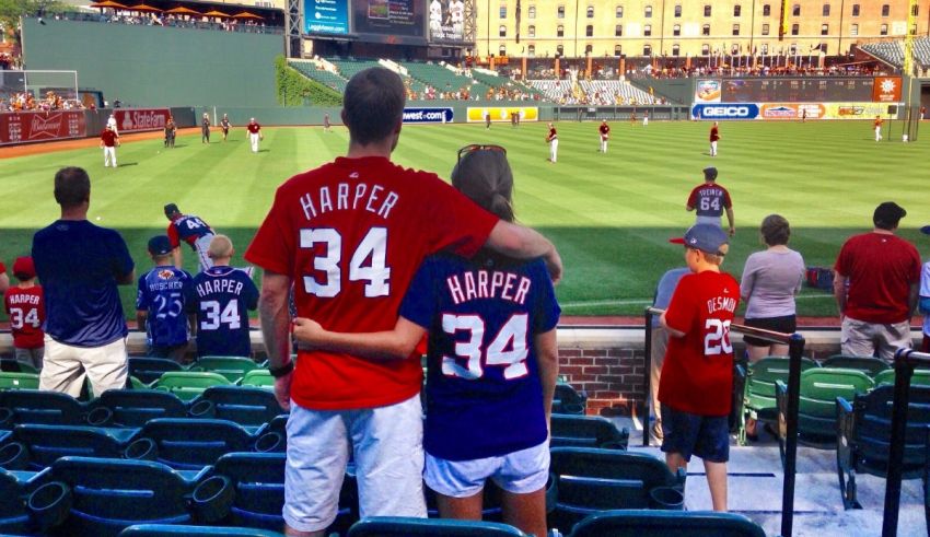 A couple sitting in the bleachers at a baseball game.