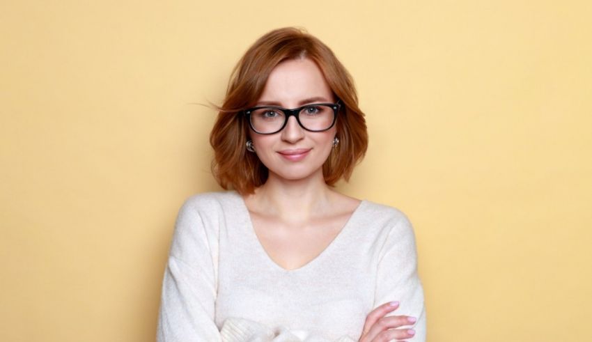 A young woman in glasses is posing against a yellow background.