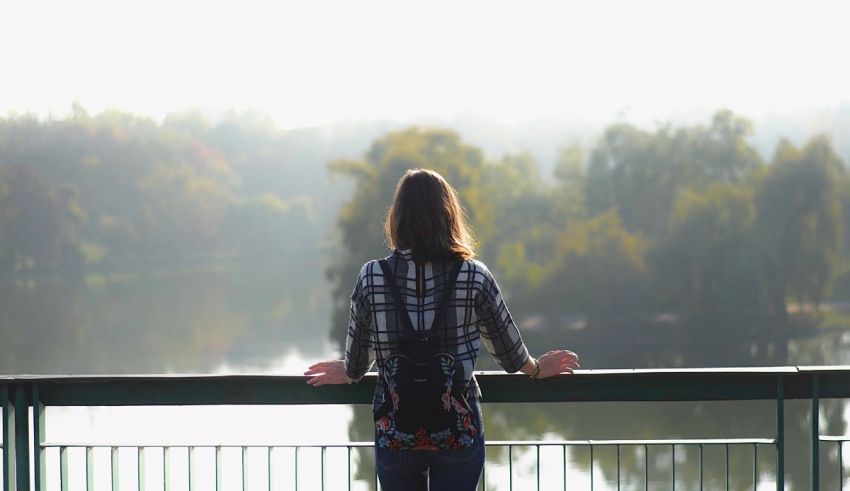A woman standing on a railing overlooking a river.