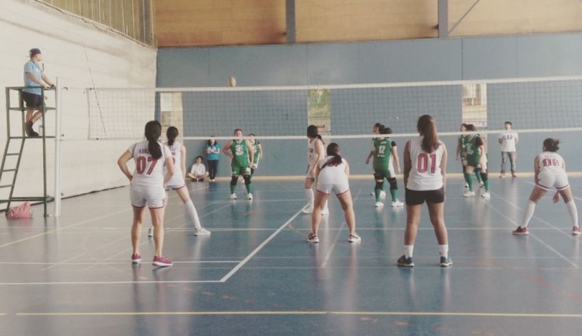 A group of girls playing volleyball in a gym.