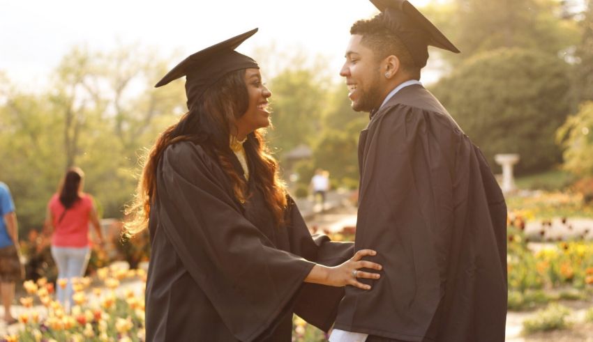 A couple in graduation gowns standing in a park.