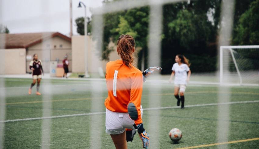 A girl in a soccer uniform is preparing to catch a ball.