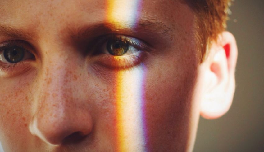 A close up of a boy's face with a rainbow in the background.
