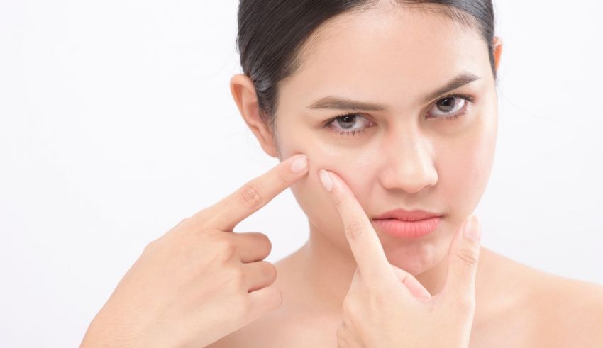 A woman is putting her finger on her face.