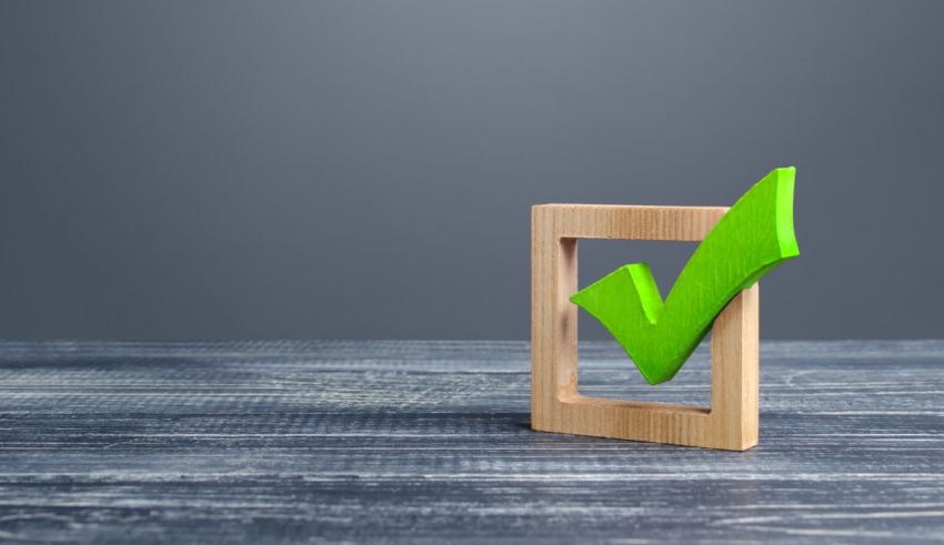 A green check mark on a wooden frame on a grey background.