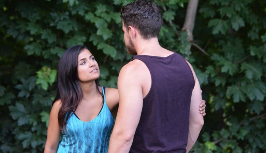 A man and woman standing next to each other in the woods.