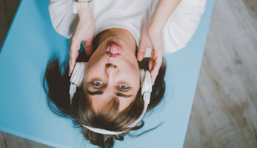 A woman is laying on a blue table with headphones on.