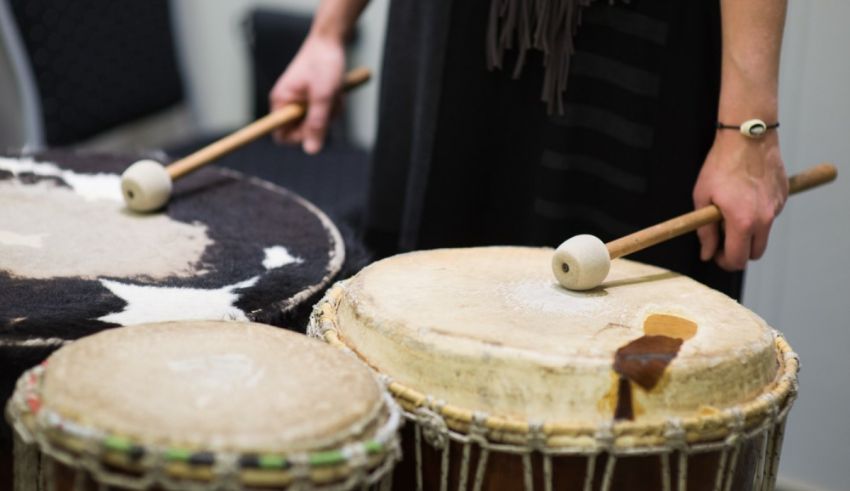 A woman is playing a djembe drum in a room.