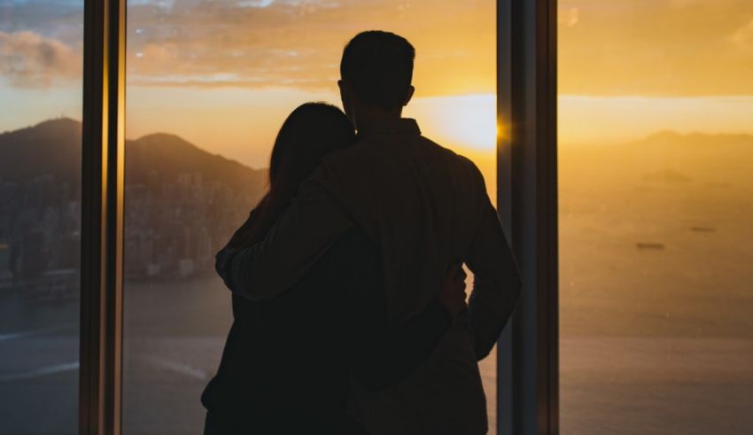 A couple looking out of a window at sunset in hong kong.