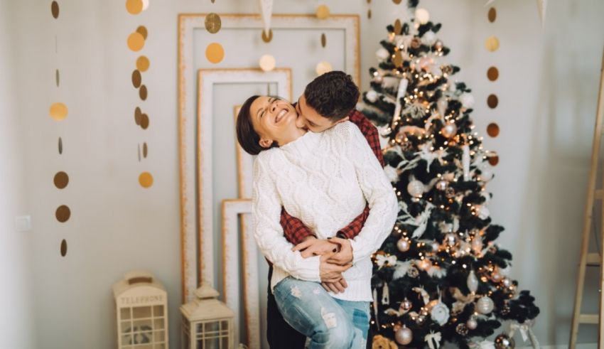 A couple hugging in front of a christmas tree.