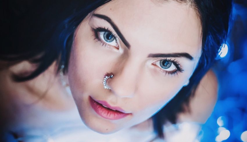 A woman with blue eyes posing in front of a blue light.