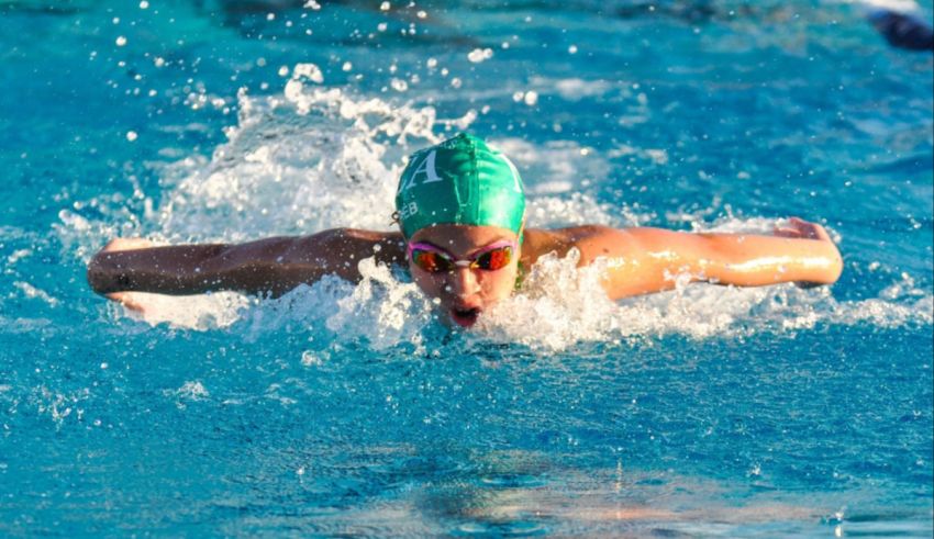 A swimmer in a green cap is swimming in a pool.