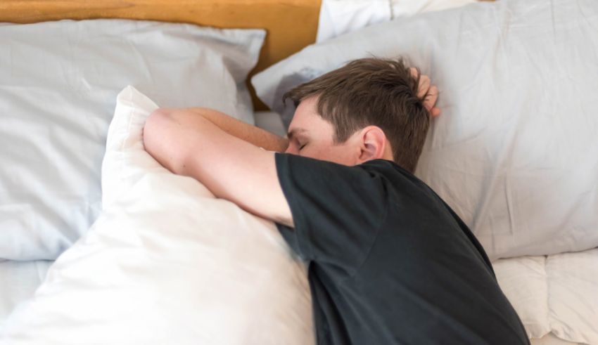 A man laying in bed with his head resting on his pillow.