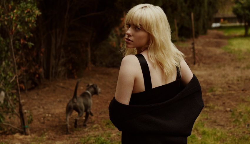 A woman in a black dress standing next to a dog.