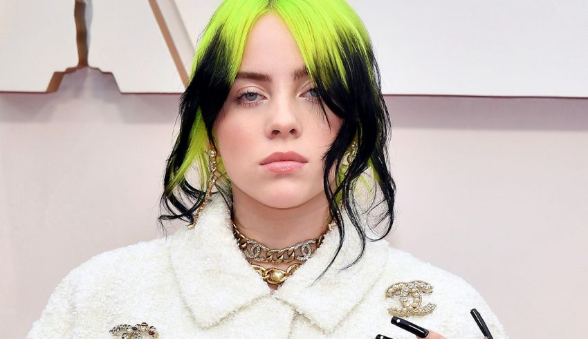 A woman with neon green hair and nails posing at the oscars.