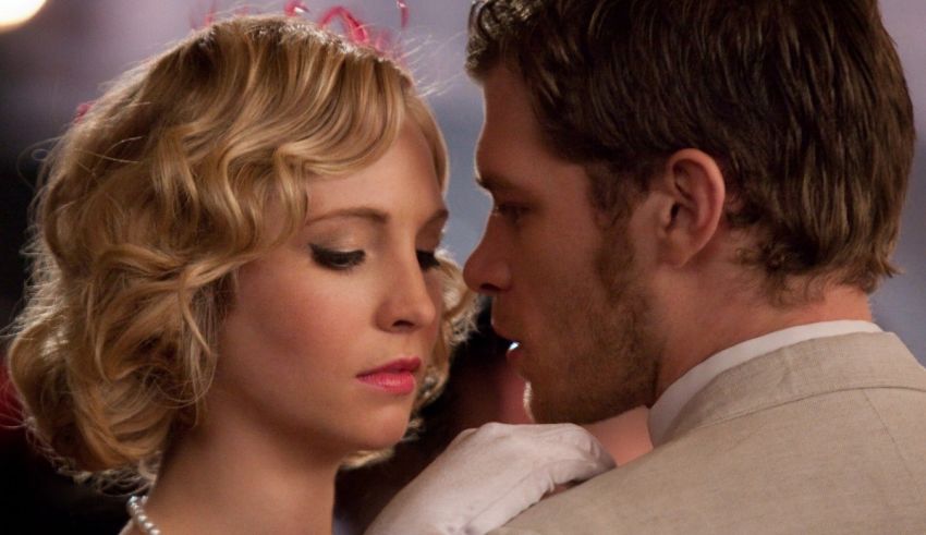 A man and woman kissing in front of a mirror.