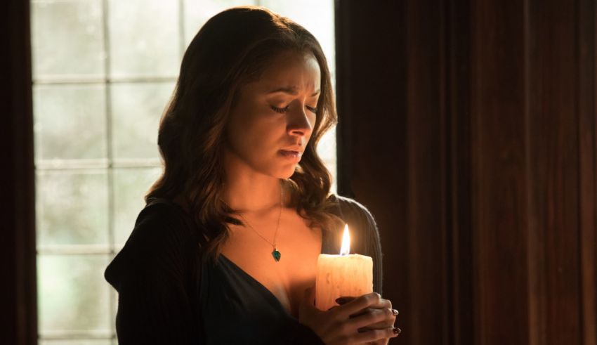 A woman holding a candle in front of a window.