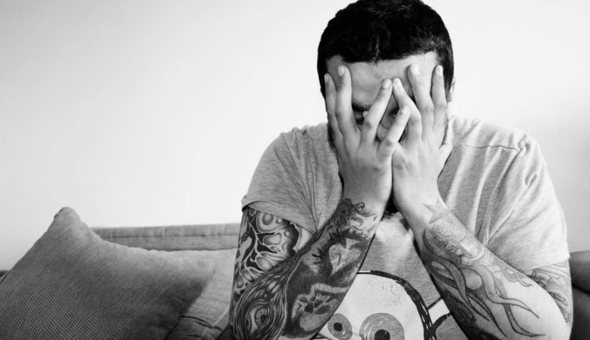 A man sitting on a couch with tattoos on his face.