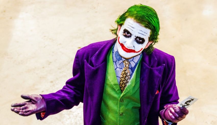 A man dressed as the joker is holding a cell phone.