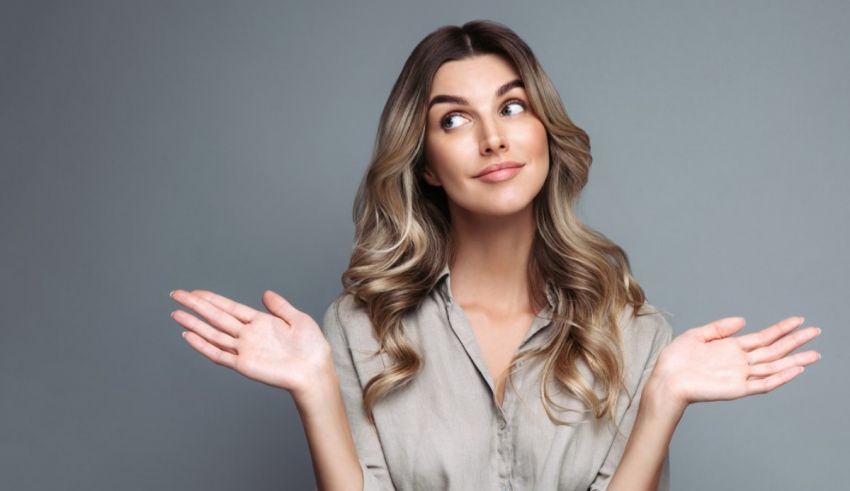 A young woman with her hands outstretched in front of a gray background.