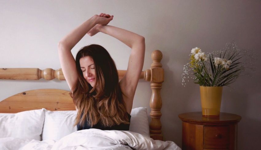 A woman stretching her arms in bed.