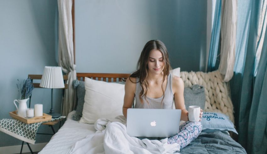 A woman sitting on a bed using a laptop.