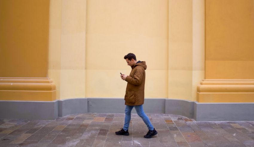 A man is walking down a street looking at his phone.
