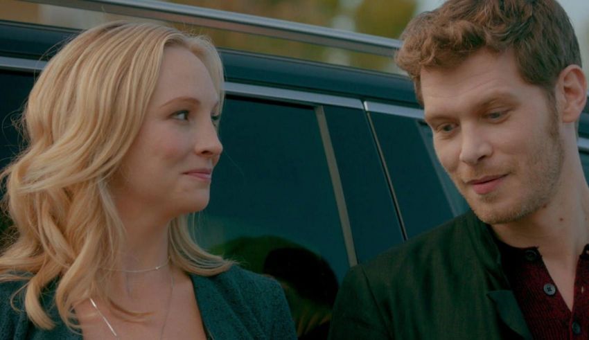 A man and a woman standing next to a car.