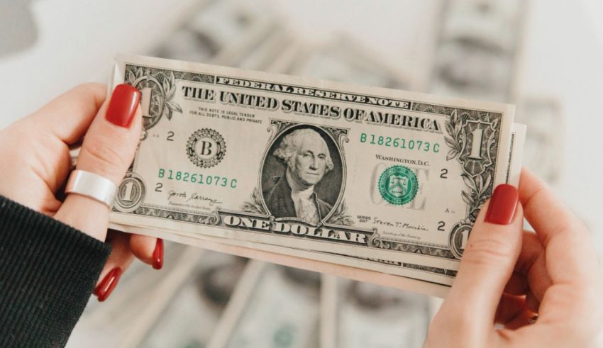 A woman's hands holding a stack of dollar bills.