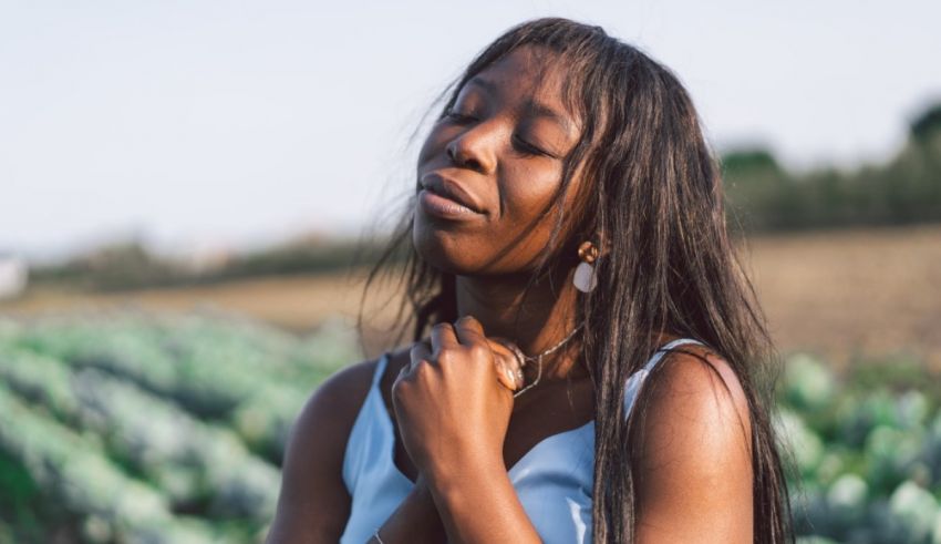 A young black woman standing in a field of vegetables.