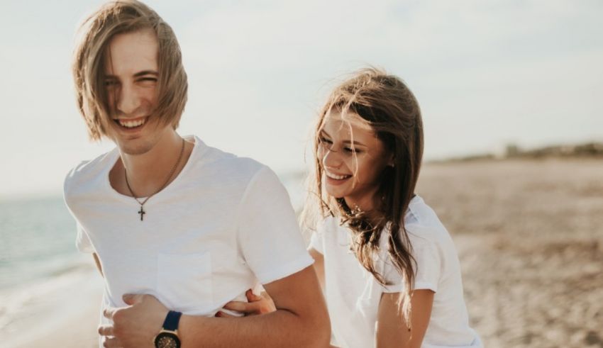 A young man and woman are walking on the beach.