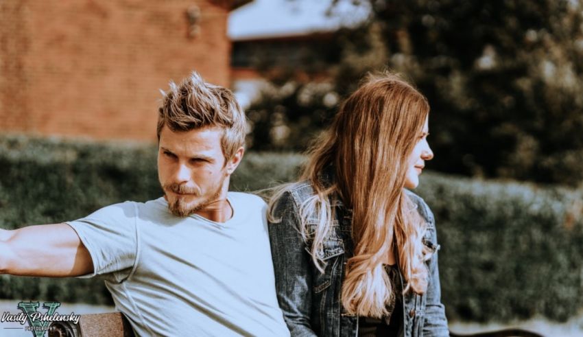 A man and woman sitting on a bench looking at each other.