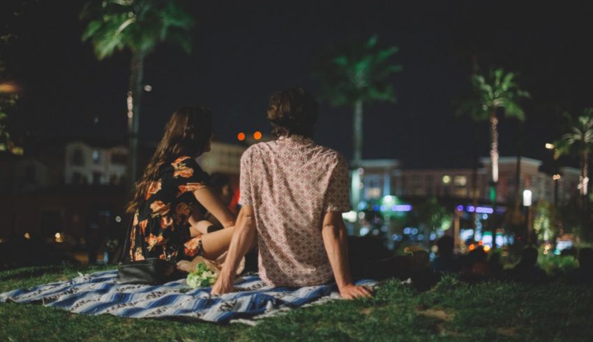 Two people sitting on a blanket in the grass at night.