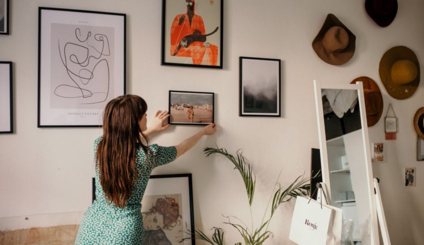 A woman looking at framed pictures on the wall.