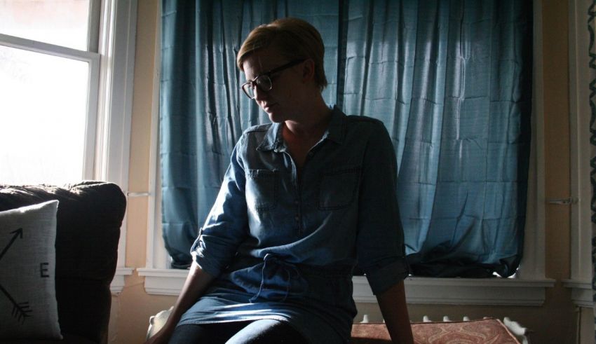 A woman in a denim shirt sitting on a couch.