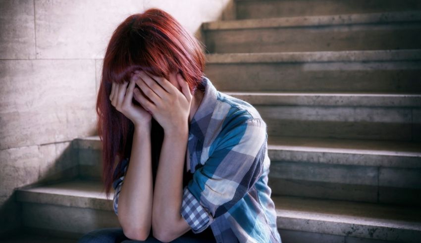 A girl sitting on the stairs with her hands on her face.