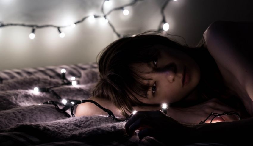 A woman laying on a bed with christmas lights.