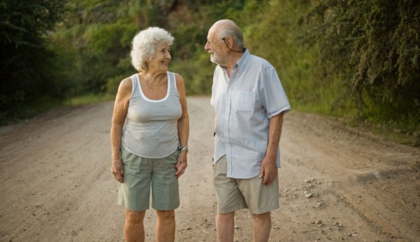 An elderly couple walking down a dirt road.