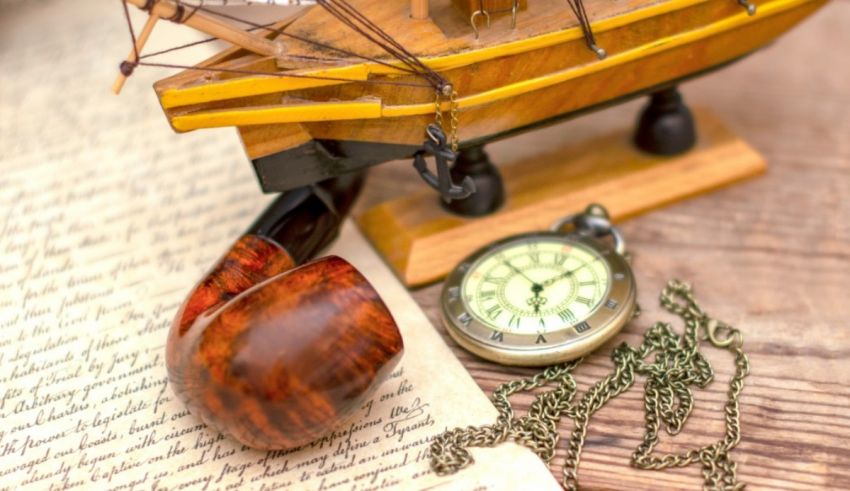 A wooden boat with a pipe and a pocket watch on a wooden table.