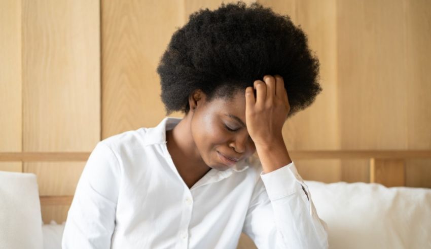 A black woman sitting on a bed with her head on her head.