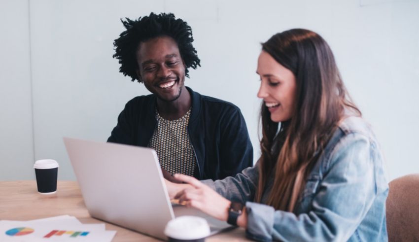 Two women working on a laptop in an office.