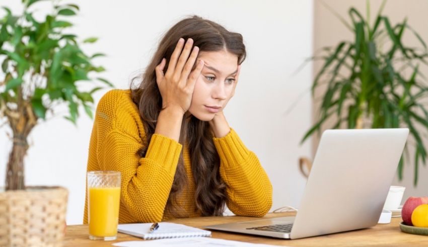 A woman is sitting at a table with a laptop in front of her.